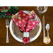 A festive table setting featuring a silver plate, red napkin with snowflakes, and utensils.