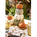 4 Flannel pumpkins stacked on top of each other resting on a table set with cloth, napkins, and glasses.