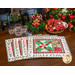 Set of 4 Christmas placemats fanned on a brown table with Christmas decorations and black chairs in the background