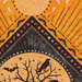 A close image of black and orange fabric quilt panel with moon phases, black cats, ravens, and a bare tree