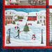 A winter scene quilt depicting ice skaters, a Christmas tree, and snow-covered houses.