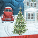 A winter scene quilt featuring a red truck, a green Christmas tree, and a blue house with snow.