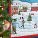 Quilted scene of a winter village with ice skaters, a snowman, and a decorated tree near festive buildings.