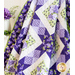 A quilt with sawtooth star design with geometric patchwork in Purple, white, and green floral fabrics draped over furniture.