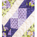 A quilt with sawtooth star design with geometric patchwork in Purple, white, and green floral fabrics.