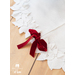 All white tree skirt with a border of layered fabric flowers and foliage with a red bow.