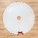 All white tree skirt with a border of layered fabric flowers and foliage.