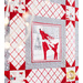 Side angled close up of a block featuring a reindeer wearing a white scarf with red accents and a gray border with sawtooth quilt star blocks at each corner