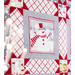 Side angled close up of a block featuring a snowman with red accents and a gray border with sawtooth quilt star blocks at each corner