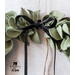 Close up image of green felt leaf decoration with thin black velvet ribbon tied in a bow