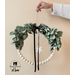 Vintage Winter Hoop Wreath held suspended by someone just off camera against a beige wall