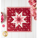 Square folded star hot pad made with red and pink floral fabrics on a white countertop with a bouquet of pink roses nearby and a heart shaped dish full of pink and red buttons