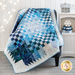 Quilt woven with blue and white fabrics draped over a chair with a white shelf and winter decorations in the background