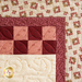 close up of top right corner of the wall hanging showing a red and pink checker pattern and floral border