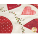 close up of embroidery detail of leafy vines with red berries and alternating pink and red hearts circling a red circle on a white background