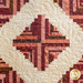 Close up of the center of the quilt with geometric patterns and negative space in the shape of a cream colored diamond