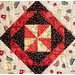 close up of quilt center with a geometric diamond pattern made up of triangle shapes in dark brown, red, and cream fabrics