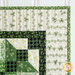 close up of wall hanging corner showing a mitered corner made with white and green shamrock fabric and a darker border with the beginning of the geometric design in the center