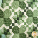 Angled image of quilting detail at the center of the wall hanging showing four shamrocks and a crossed geometric pattern made up of small squares and triangles