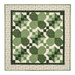Small quilt wall hanging featuring pieced shamrocks with geometric designs all in green and cream isolated on a white background