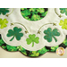 Close up of edge of table topper showing shamrocks, metallic hand embroidery details with small old beads, and a scalloped border made with leaf patterned fabrics
