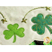 Close up of edge of table topper showing shamrocks and metallic hand embroidery details with small gold beads