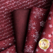 Close up of dark red fabric with metallic silver winter motifs and script patterns layered atop one another