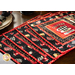 image of four placemats made with the Coffee Always fabric collection featuring red, black, and neutral tones with coffee mugs and coffee beans, fanned out on a brown table with ornate cream plates and napkins in the background