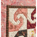 close up of the top left corner and a block of the mini quilt featuring a swirl with opposing curved shapes from each corner in cream and pink patterned fabrics framed on two sides by a brown strip of fabric and a pink paisley-like floral border