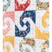 close up of a few blocks from the mini quilt featuring a swirl with opposing curved shapes from each corner in white and differently colored patterned fabrics