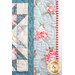 close up of the edge of a patchwork quilt with classic quilt star blocks in soft blue, pink, and cream, showing floral fabrics patterns and quilting detail