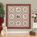 Photo of a square quilt featuring a house and floral motifs in each block hanging on a gray wall with burgundy and white home decor on white furniture pieces