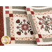 Close up photo of two draped quilt blocks featuring floral motifs made with neutral and red colored fabrics