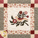 Close up of a quilt made with neutral and burgundy fabrics depicting a bird perched on a branch