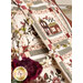 Close up photo of draped quilt blocks featuring floral motifs made with neutral and red colored fabrics with flowers in the foreground