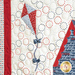 close up of quilted kite in the top left corner sporting red and white quadrants and a blue tail with bows on a white background covered with rings of blue and red stars.
