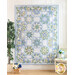 Photo of a blue, cream, and green floral quilt with octagonal blocks hanging on a white paneled wall with a houseplant and small white chair with blue flower decorations