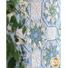 Angled photo of a blue, cream, and green floral quilt with a green houseplant in the foreground