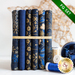 6 folded dark blue fabrics with gold metallic motif accents propped vertically bound with a gold ribbon on a white countertop with gold and blue spools of thread and a large blue bauble to the right of it, with a gold star decoration in the background and a green banner in the top right corner that reads 