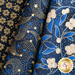 Close up of dark blue fabric with metallic gold winter motifs layered atop one another