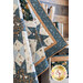 a small blue and white quilt with sawtooth star shapes and square diamonds made with the Little Forest fabric collection hanging draped from a brown paneled wall with a small shelf in the background