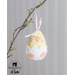Close up of a pale yellow easter egg ornament with a white broken shell, orange feet, and a small chick face hanging by a pink ribbon on a branch.