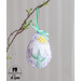 Close up of a pale purple easter egg ornament hanging by a teal ribbon on a branch with a white daisy with a yellow center and green stem.