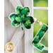 Close up image of a shamrock and the letter L with painted wooden beads between them hanging in front of a whitewashed timber framed shutter and window pane