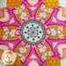 Close up image of the center of the quilted flower design on the top of the pincushion with pink and gold fabric, bees, and a center piece made to look like the center of a flower with green accents