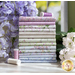 Stack of folded fabrics included in the Sugar Lilac FQ set with coordinating threads and flowers on display.