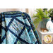 A vibrant quilt in shades of blue with marine patterns, draped over a chair near coastal decor.