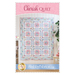 Front of the pattern booklet showing the finished quilt hanging on a white paneled wall with the title at the top