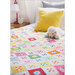 A white quilt with colorful blocks draped over a bed with a yellow pillow and small stuffed animal
