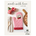 front cover of the Made With Love Oven Mitt Pattern booklet featuring a photo of a pink oven mitt with red trim and a white circle depicting strawberries and the words 